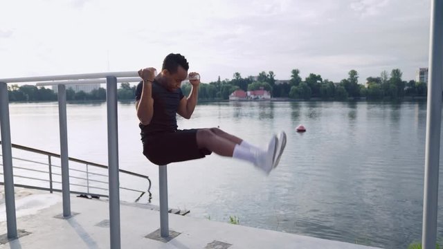 Muscular man doing abdominal exercises near the lake