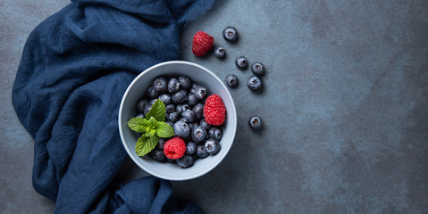 Fresh and sweet blueberry and raspberry in bowl with classic blue napkin  on dark blue wood...