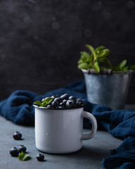 Fresh and sweet blueberry in cup with mint and wet on dark  wood background