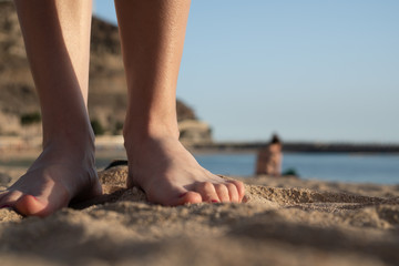 Closeup of a woman's legs and feet with nail polish on the sand in a beach.  Summer holidays in Puerto Rico, Gran Canaria, Spain, beach resort and vacations concept