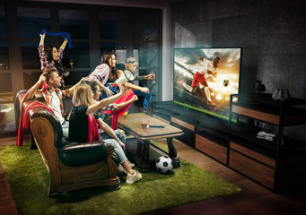 Fototapeta Group of friends watching TV, football match, sport together. Emotional men and women cheering for favourite team, look on goal and fighting for ball. Concept of friendship, leisure activity, emotions obraz