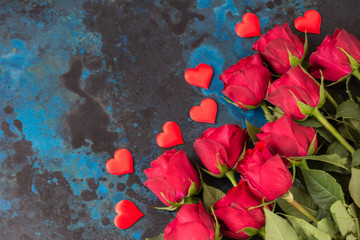 on a blue background a bouquet of red roses and satin hearts