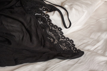 Black lace underwear lying on bed sheet. Close up image.