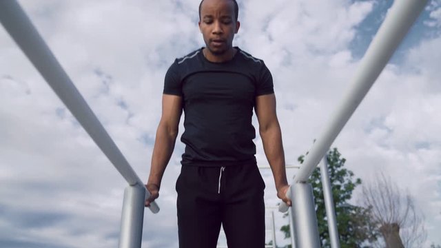 Afro american athlete doing parallel bars abdominal exercise