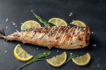 baked mackerel with lemon and spices on a stone background, ready to eat
