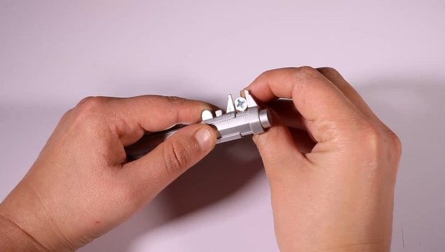 Person measuring with a vernier caliper for greater accuracy