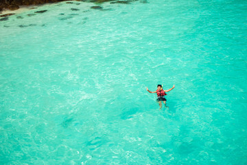 Fototapeta premium Young man snorkeling in clean water over coral reef.