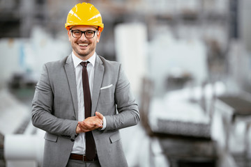 Portrait of successful businessman in factory. Handsome architect in suit. 