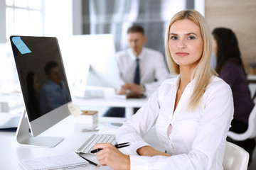 Obraz premium Business woman using computer at workplace in modern office. Secretary or female lawyer smiling and looks happy. Working for pleasure and success