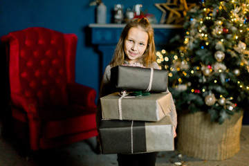 Little beautiful girl holds christmas gifts and happy from this.