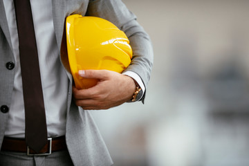 Close up of businessman in suit holding helmet. 