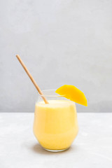 Mango Lassi in a glass cup on neutral grey background