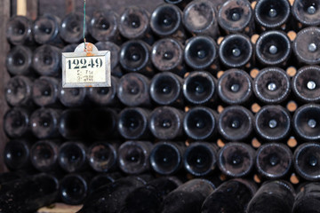 Closeup pattern from bottom of old dark dusty wine bottles in rows in cellar, basement, wine warehouse, winery. Concept vault with old rare wines, exclusive collection rare bottle. Mosaic background