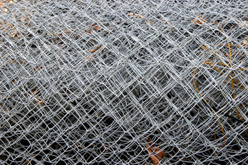 Surface of a big roll of damaged wire netting with diamond-shaped elements 