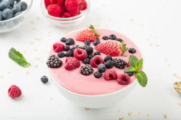 Smoothie bowl with yogurt, muesli and frozen berry. Pink yogurt smoothie bowl topped with frozen berries raspberries, strawberries, blackberries and blueberries. Healthy summer dessert. 