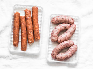 Raw uncooked turkey and spicy smoked paprika pork homemade sausages on light background, top view. Food ingredients