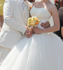 wedding couple hugging, the bride holding a bouquet of flowers in her hand, the groom embracing her