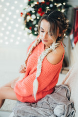 Obraz na płótnie Canvas Attractive beautiful girl with two boxer braids, with bare legs in a sweater on the background of Christmas decorations