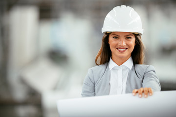 Young businesswoman with blueprint. Portrait of female architect in factory.