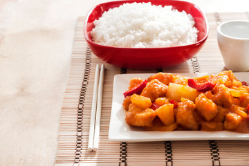 Sweet and sour chicken with bell pepper and pineapple. White rice on background