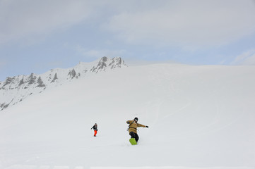 Naklejka na ściany i meble Two snowboarders gliding from top of mountain