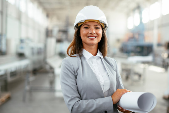 Young businesswoman with blueprint. Portrait of female architect in factory.