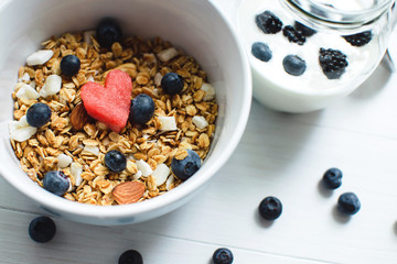 watermelon slices with heart-shaped, almonds, blueberries on a white wooden table with granola in bowl