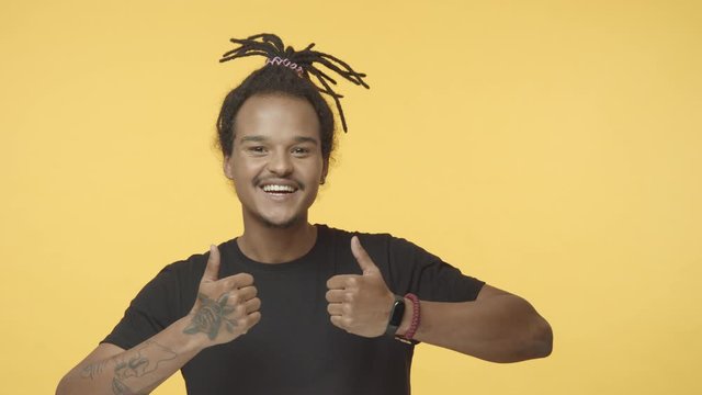 Yeah man lets do it. Cheerful and outgoing good-looking african american young tattoed hipster guy in black t-shirt with dreadlocks combed, show thumb-up and nod approval, agree, like idea