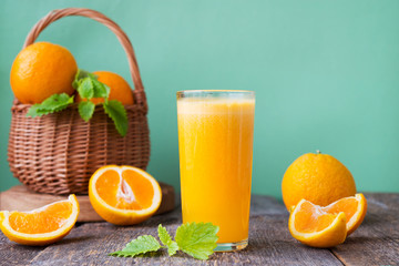 A glass of freshly squeezed juice surrounded by fresh oranges and tangerines. Horizontal photo.