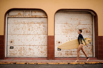 Surfer girl walking confidently with a surfboard