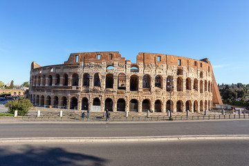 Historic monument, Colosseum in spring with walking tourists in the Italian city of Rome.