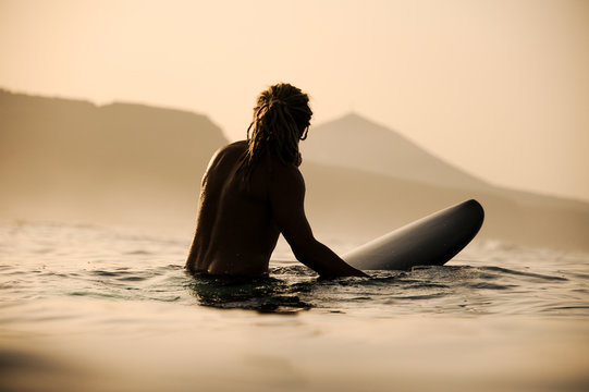 Silhouette of shirtless surfer in the waters