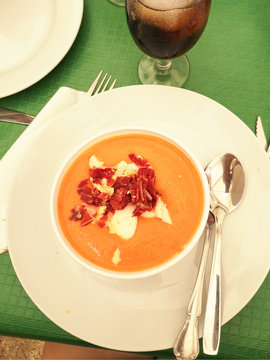 Pumpkin soup with bacon and sour cream on a white plate with a tablespoon