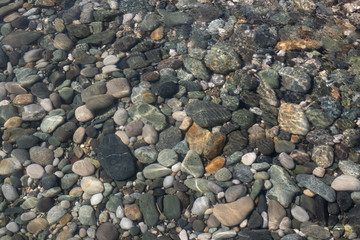 Sea stones in the sea water. Pebbles under water. The view from the top. Nautical background. Clean sea water. Transparent sea.