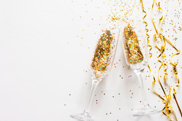 champagne glasses and scattered confetti on a white background with place for text. christmas new year holiday concept © itakdalee
