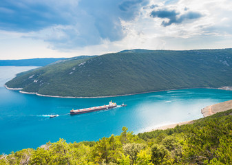 Obraz premium Barge and escort boats sailing through the Plomin bay in Istria, Croatia