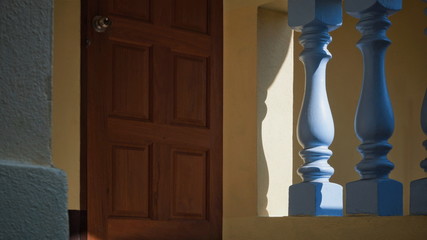 Sunlight and shadow on surface of vintage blue stone balusters with blurred wooden door in yellow...