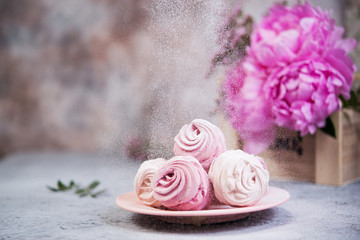 Homemade berry marshmallow in a plate is on the table with a Cup of tea. Powdered sugar falls on top of marshmallows..