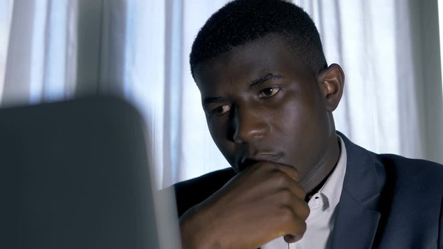 young black african man shaking his head and looking at computer screen