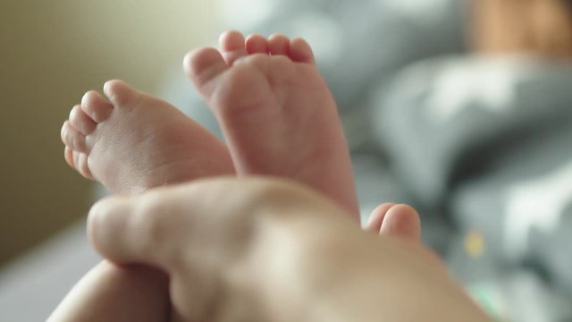 Mother touching her newborn son feet with tender.