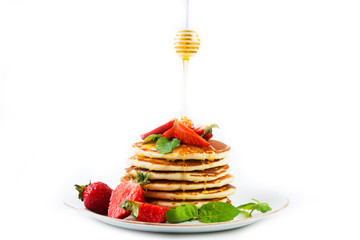 American pancakes lined with strawberries and honey poured on a white background. Horizontal photo. Classic American Breakfast.