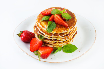 American pancakes lined with strawberries and honey poured on a white background. Classic American Breakfast.