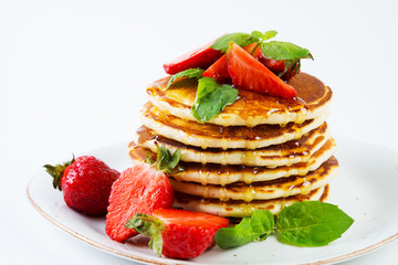American pancakes lined with strawberries and honey poured on a white background. Classic American Breakfast.