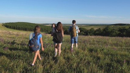 travelers admire the beautiful scenery and nature. teamwork of tourists. travelers go with backpacks through meadow. Family of tourists with children in the countryside. movement to victory.