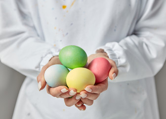 Girl's hands with handmade colored eggs on a white background. Copy space. Preparation for celebration Easter.
