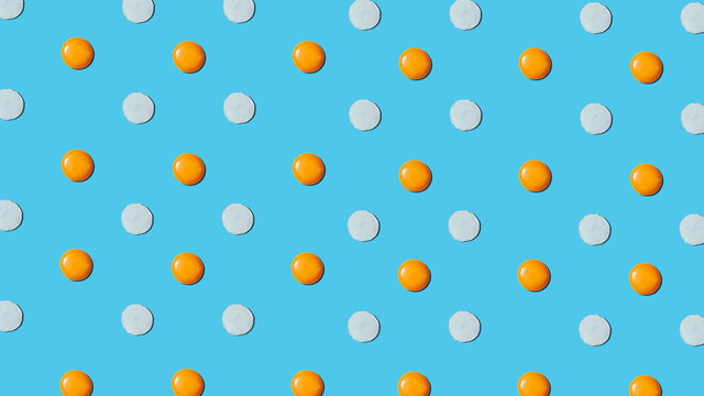 Food pattern with raw natural eggs yolks and eggwhite on a blue background.