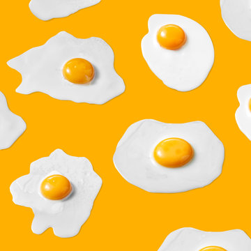 Food pattern from fried eggs with yolks on a yellow background.