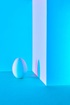 Vertical egg in a blue red tones with shadow on a wall on a blue background.