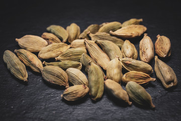 Macro view of green cardamom seeds in black slate background. 
