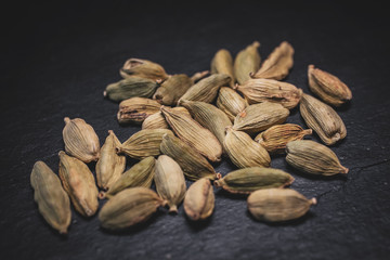 Macro view of green cardamom seeds in black slate background. 